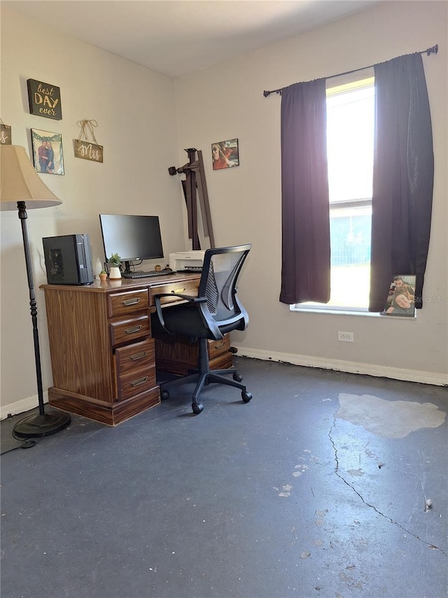 home office featuring concrete floors and baseboards