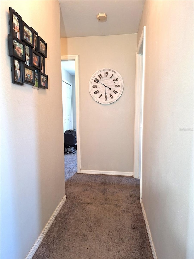 hallway featuring carpet flooring and baseboards