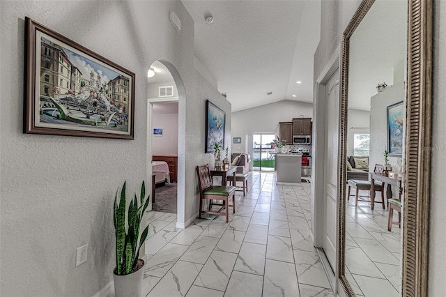 hallway featuring light tile patterned floors and vaulted ceiling