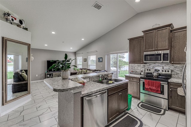 kitchen featuring light tile patterned flooring, an island with sink, tasteful backsplash, and stainless steel appliances