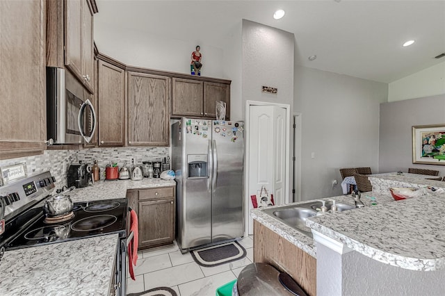 kitchen featuring light tile patterned flooring, sink, appliances with stainless steel finishes, decorative backsplash, and vaulted ceiling