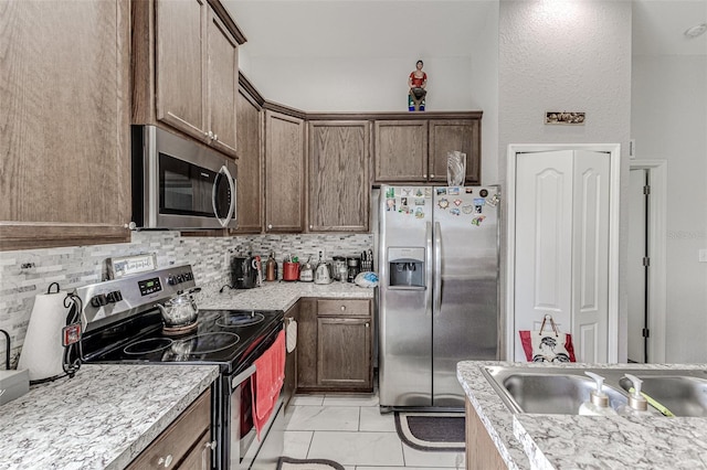 kitchen featuring sink, backsplash, appliances with stainless steel finishes, and light tile patterned floors