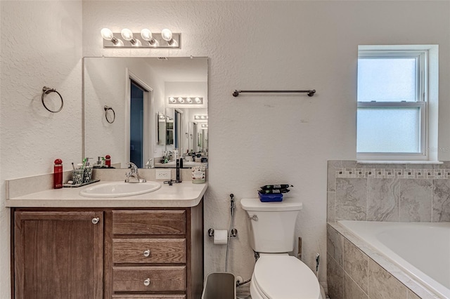 bathroom featuring a relaxing tiled tub, toilet, and vanity