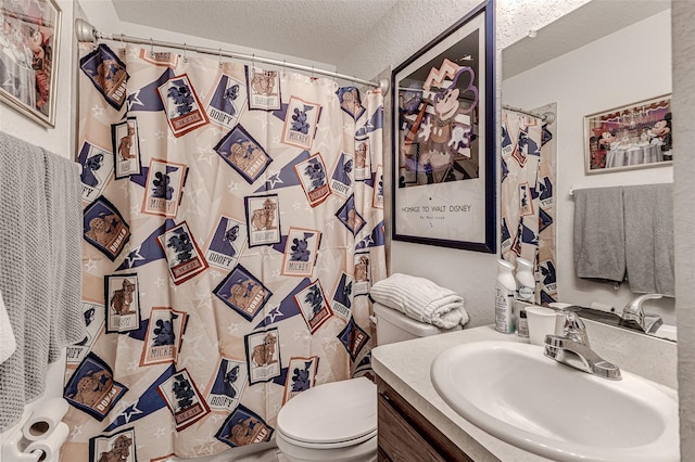 bathroom with a textured ceiling, vanity, and toilet