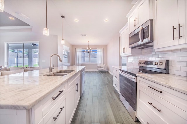 kitchen with hanging light fixtures, wood-type flooring, tasteful backsplash, stainless steel appliances, and white cabinets