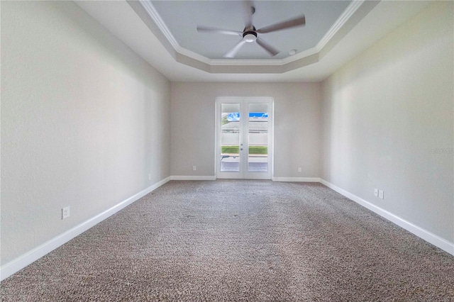 carpeted spare room with a tray ceiling, ceiling fan, crown molding, and french doors