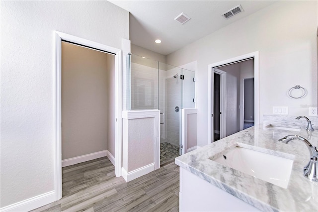 bathroom featuring double sink, a shower with door, and hardwood / wood-style floors