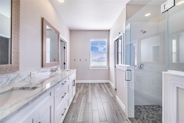 bathroom featuring double vanity, a shower with door, and hardwood / wood-style floors