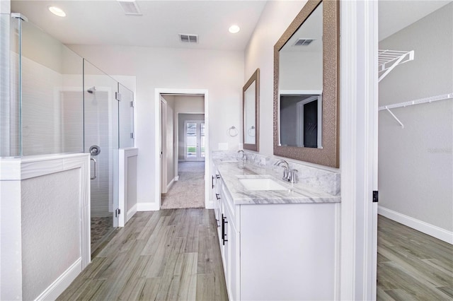 bathroom featuring hardwood / wood-style floors, double vanity, and an enclosed shower