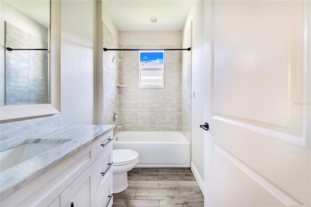 full bathroom featuring toilet, tiled shower / bath combo, vanity, and hardwood / wood-style flooring