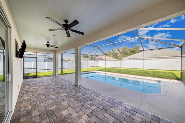 view of swimming pool with ceiling fan, a yard, a patio area, and a lanai