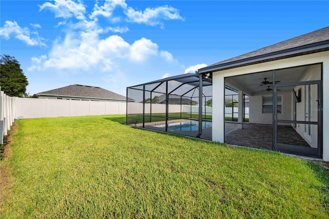 view of yard featuring ceiling fan, glass enclosure, and a fenced in pool