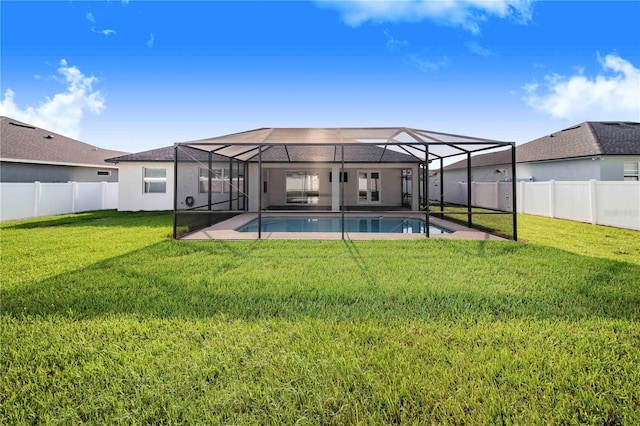 back of house featuring glass enclosure, a yard, and a fenced in pool