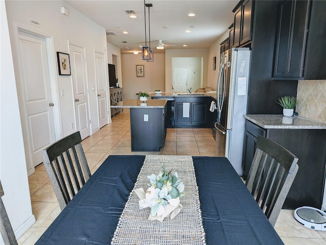 kitchen featuring light tile patterned floors, stainless steel fridge, hanging light fixtures, and a kitchen island