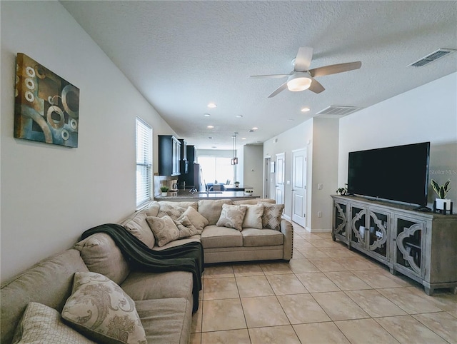 living room featuring a textured ceiling, ceiling fan, and light tile patterned floors