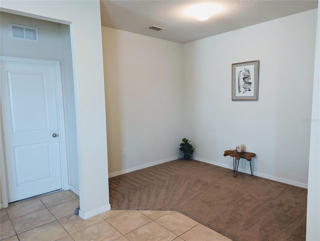 empty room with a textured ceiling and light tile patterned floors