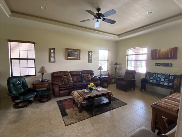 living room with ceiling fan, a raised ceiling, and light tile patterned floors