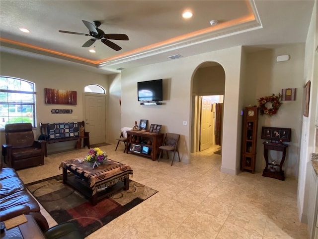 tiled living room featuring ceiling fan and a raised ceiling