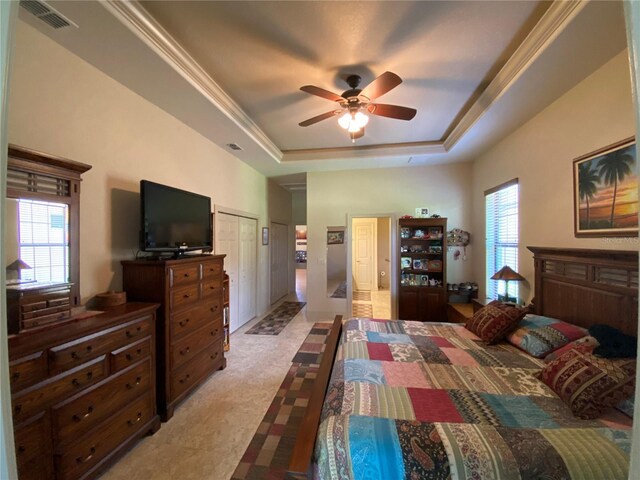 bedroom featuring ceiling fan, a raised ceiling, tile patterned floors, and multiple windows