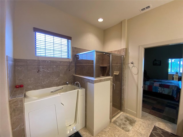 bathroom with washer / clothes dryer, shower with separate bathtub, tile patterned floors, and tile walls