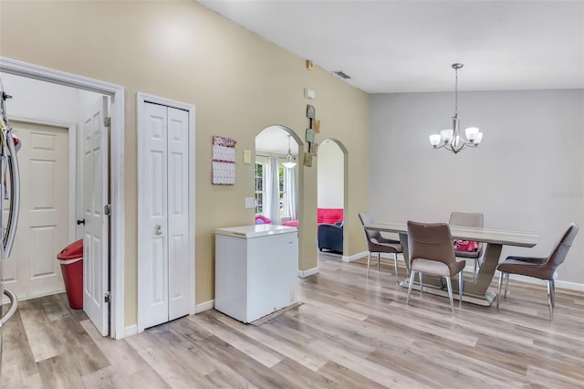 dining space with light wood-type flooring, high vaulted ceiling, and a notable chandelier