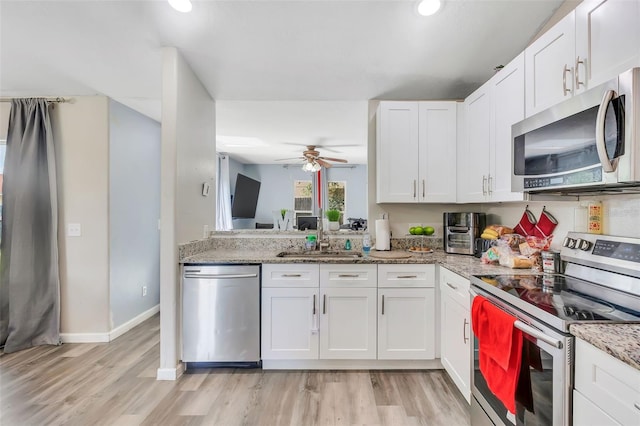 kitchen featuring ceiling fan, stainless steel appliances, light hardwood / wood-style flooring, and white cabinetry