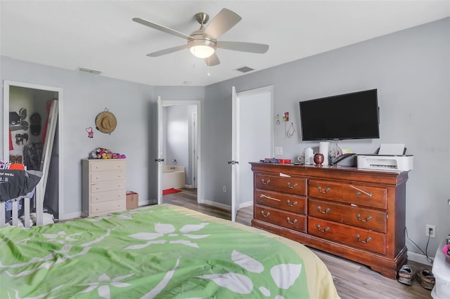 bedroom featuring light hardwood / wood-style flooring, ceiling fan, and ensuite bath