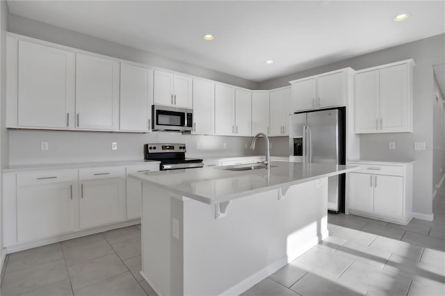 kitchen featuring sink, light tile patterned flooring, a kitchen island with sink, white cabinets, and appliances with stainless steel finishes