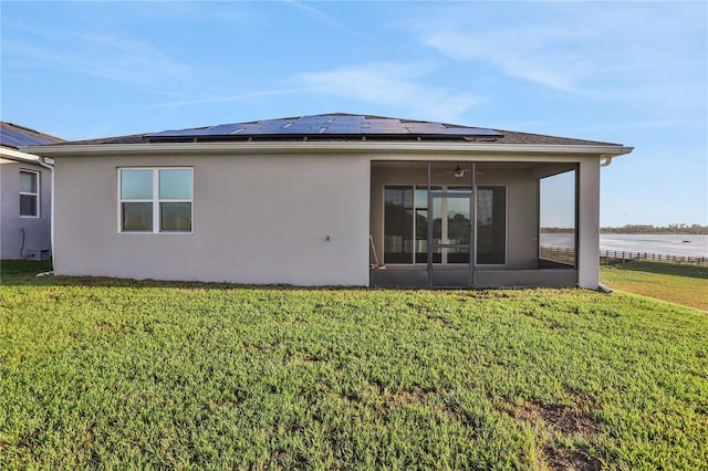 back of property featuring solar panels, ceiling fan, and a lawn