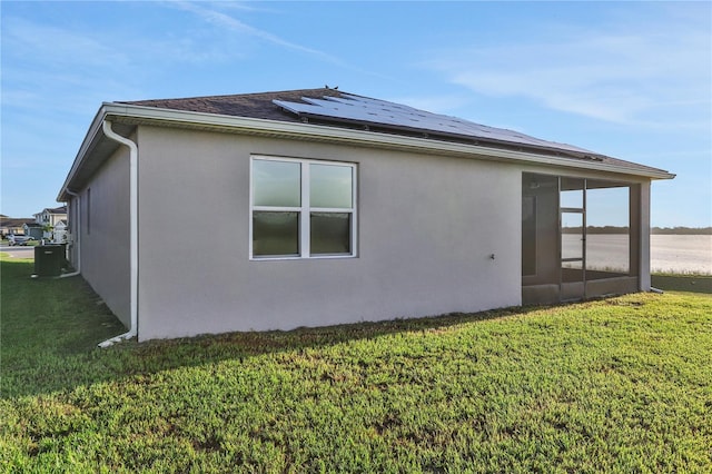 view of home's exterior with a lawn, central AC, a sunroom, and solar panels