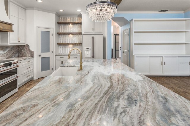 kitchen with refrigerator with ice dispenser, sink, light stone countertops, and tasteful backsplash