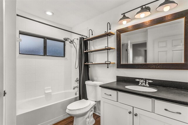 full bathroom with shower / bath combo with shower curtain, hardwood / wood-style floors, vanity, and toilet