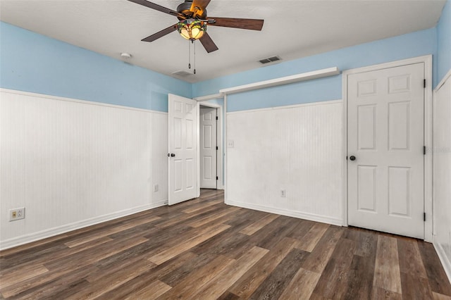 unfurnished bedroom with ceiling fan, a textured ceiling, and dark hardwood / wood-style floors