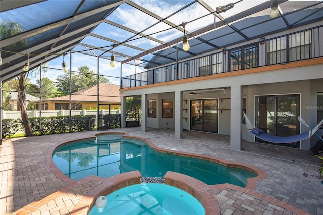 view of swimming pool featuring an in ground hot tub, a patio, glass enclosure, and ceiling fan