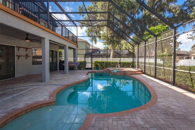 view of pool with an in ground hot tub, a patio area, glass enclosure, and ceiling fan