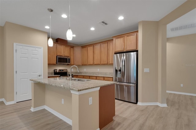 kitchen with light stone counters, sink, a kitchen island with sink, appliances with stainless steel finishes, and light hardwood / wood-style floors