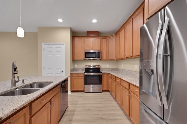 kitchen featuring pendant lighting, sink, light hardwood / wood-style flooring, stainless steel appliances, and light stone countertops