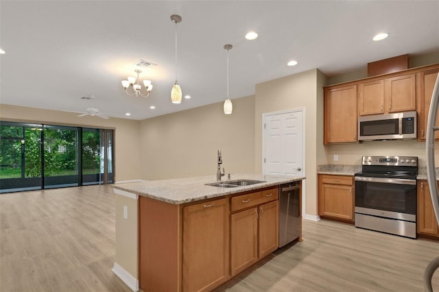 kitchen with hanging light fixtures, light hardwood / wood-style floors, an island with sink, stainless steel appliances, and sink