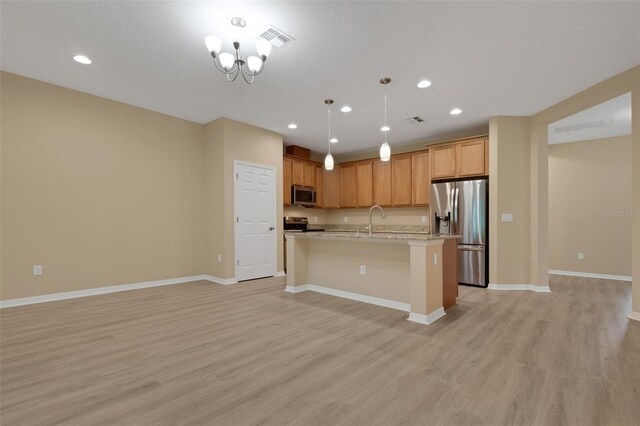 kitchen with pendant lighting, light hardwood / wood-style floors, a center island with sink, and appliances with stainless steel finishes