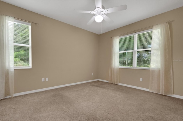 empty room with carpet floors, a healthy amount of sunlight, and ceiling fan