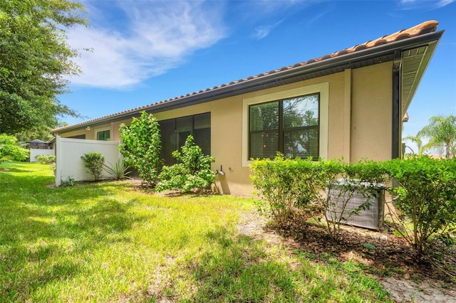 rear view of house featuring a lawn and central AC unit