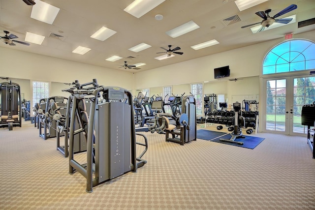 exercise room with french doors, light colored carpet, and a high ceiling