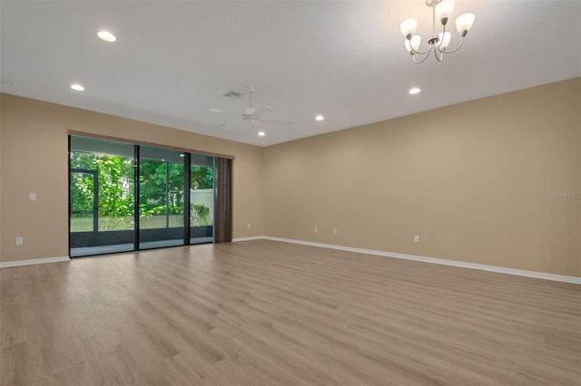 unfurnished room featuring ceiling fan with notable chandelier and light hardwood / wood-style flooring