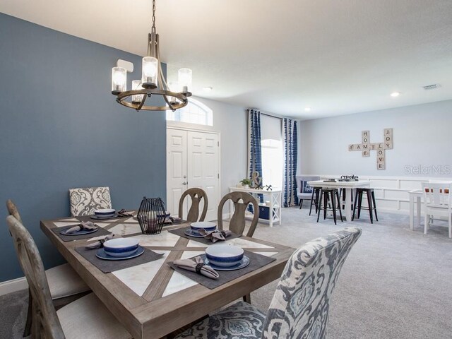 dining area with an inviting chandelier and light carpet