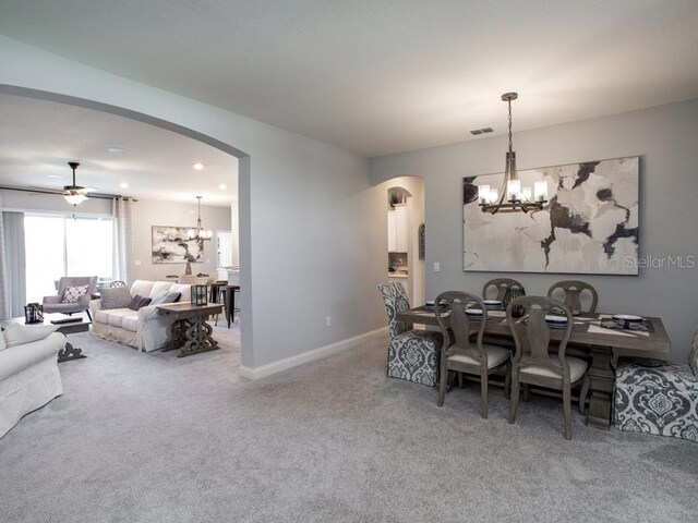 dining area with carpet floors and ceiling fan with notable chandelier