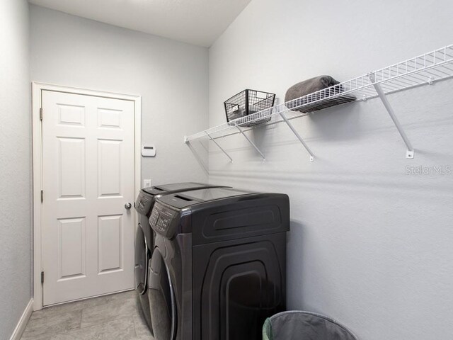 laundry room featuring light tile patterned floors and washing machine and dryer