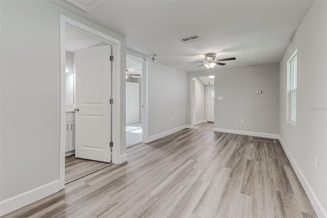 empty room featuring light wood-style flooring, visible vents, and baseboards