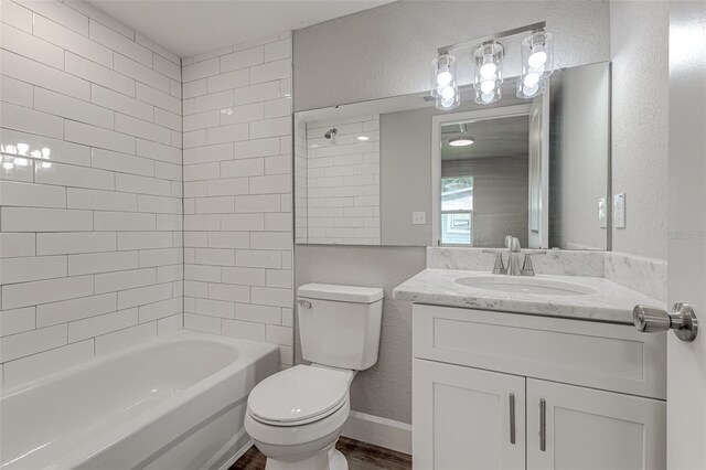 full bathroom featuring tiled shower / bath, toilet, hardwood / wood-style floors, and vanity