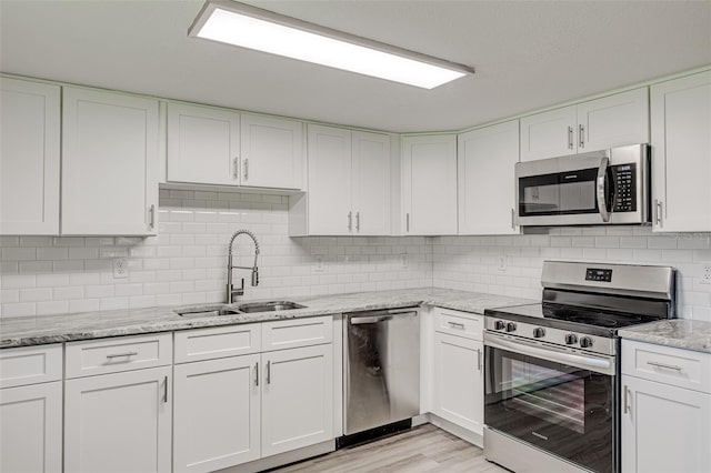 kitchen with white cabinetry, stainless steel appliances, and tasteful backsplash