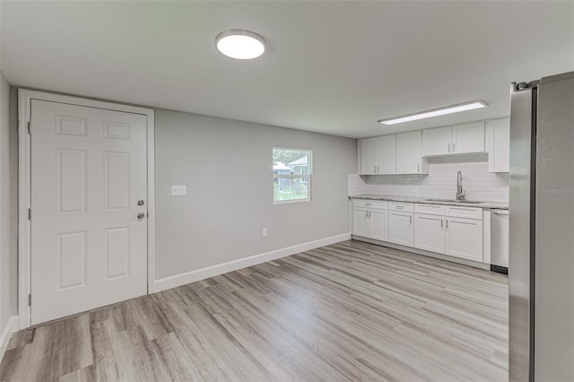 kitchen with a sink, white cabinetry, light countertops, appliances with stainless steel finishes, and decorative backsplash